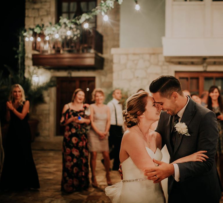 The bride and groom dancing in front of guests, nose to nose