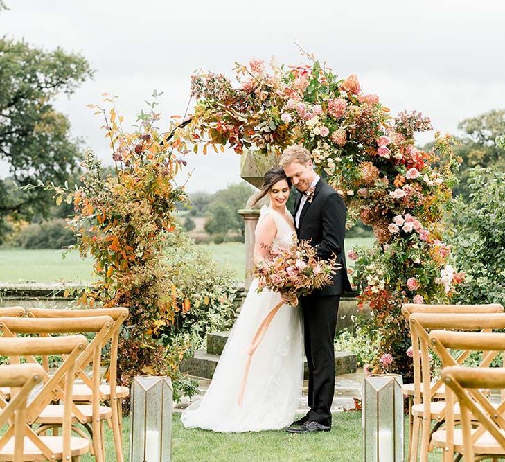 Outdoor wedding ceremony at Dorfold Hall with wooden chairs and a giant autumn flower moon gate 