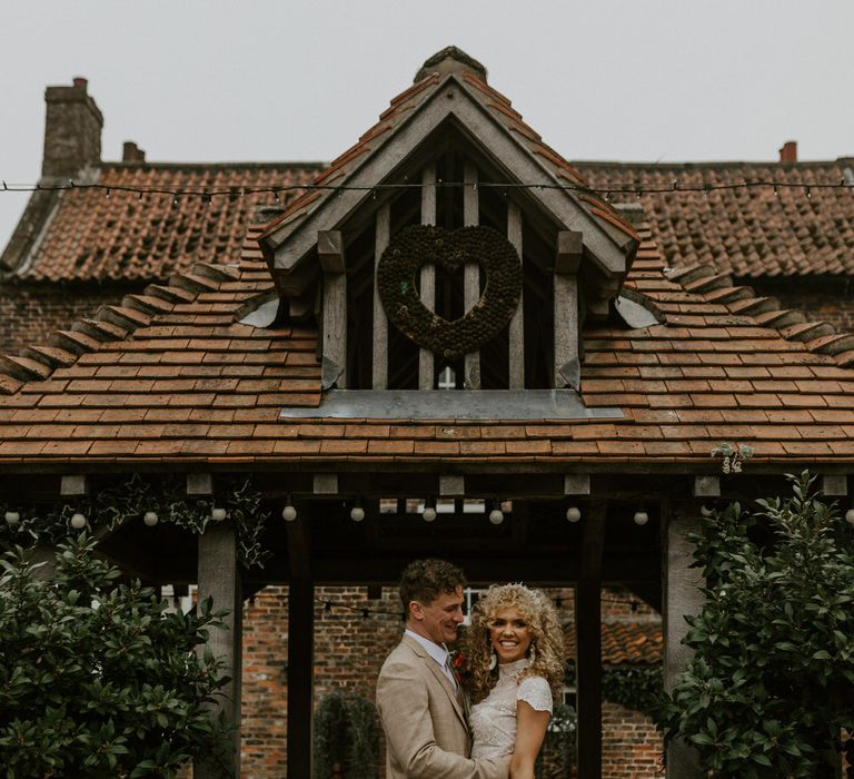 Bride and groom outside a barn, the groom holding the brides waist