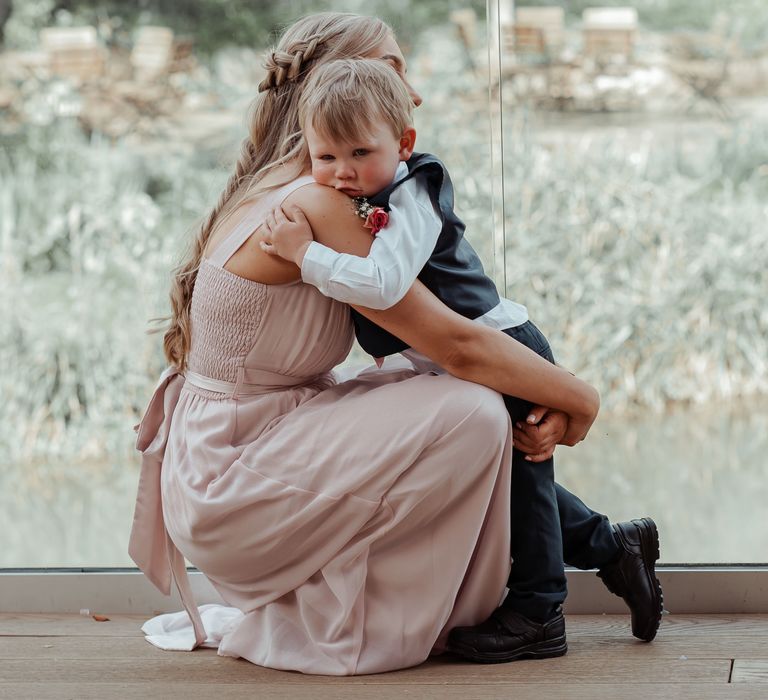 Little boy hugs bridesmaid 