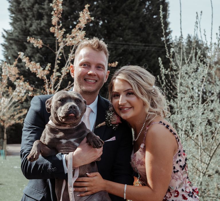 Bride & groom stand with their Staffordshire bull terrier on their wedding day