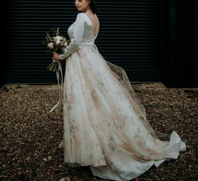 Bride in a couture wedding dress with low back detail, long sleeves and a floral chiffon skirt 