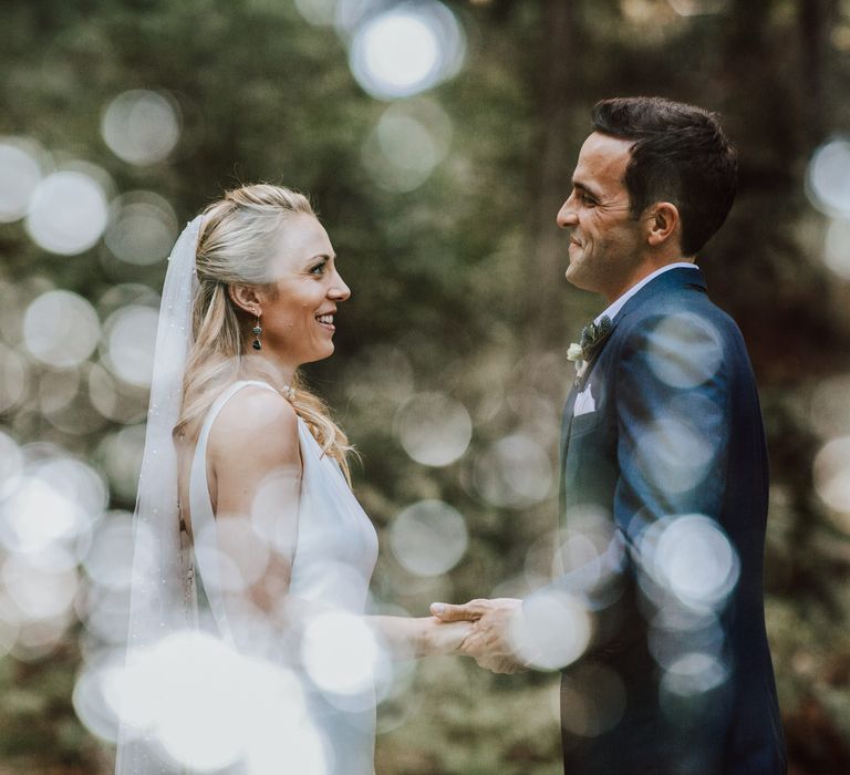 Bride & groom hold hands and smile at one another during elopement ceremony