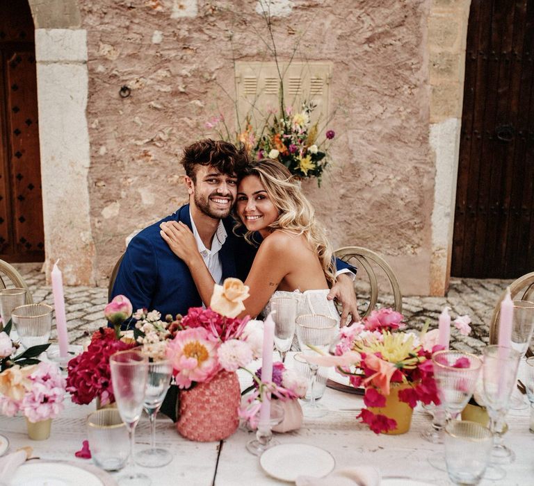 Bride and groom smiling at glamorous pink and white wedding banquet table