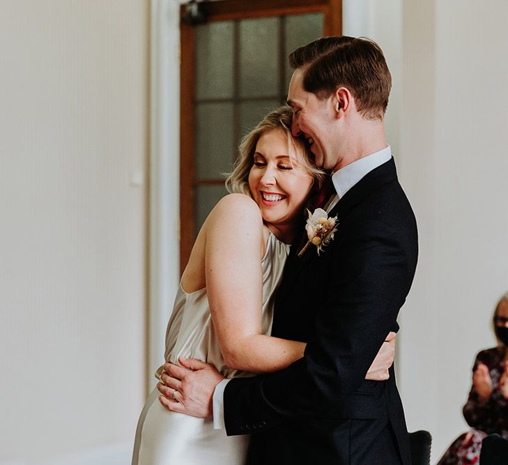 Bride in a champagne colour wedding dress by Kate Beaumont embracing her husband during their Leeds Civic Hall ceremony 