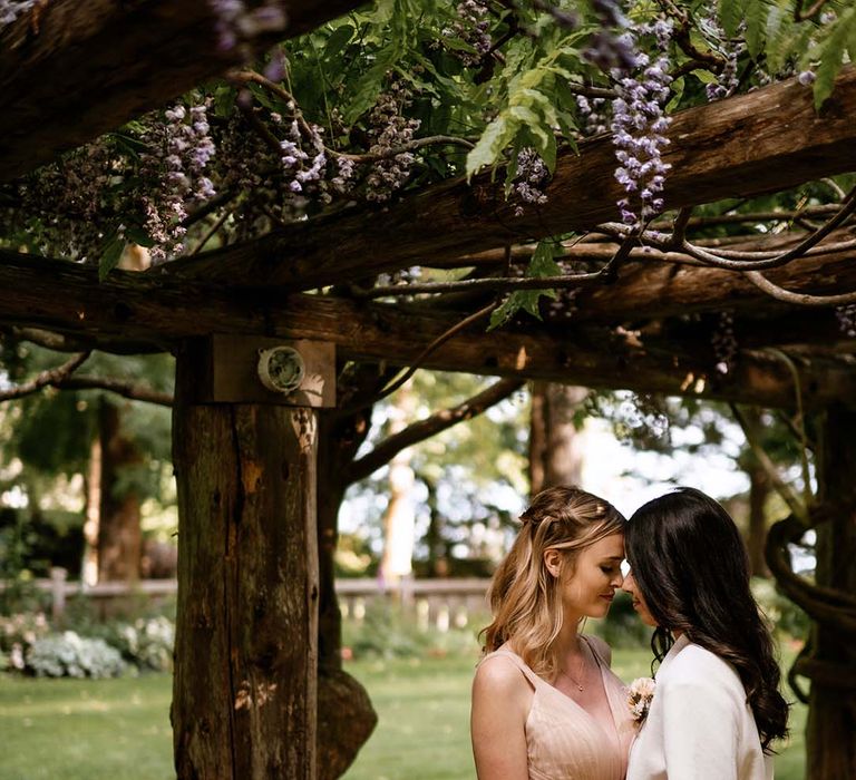 Two brides embracing at the end of their al fresco wedding reception 