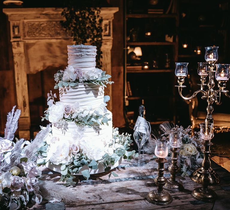 Three-tier wedding cake with ruffled white frosting and floral decor