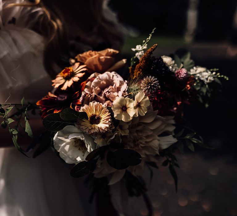 Bride in Halfpenny London Mayfair dress holding mixed bridal bouquet with yellow, pink and red flowers at wedding in Cornwall