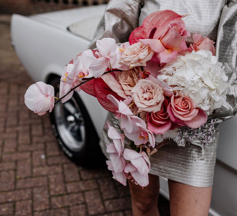 Bride holding Pink tonal bouquet full of hydrangeas, long orchids and roses