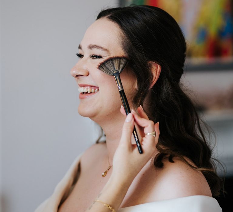 Bride has makeup applied on the morning of her wedding day as she wears her dark hair tied back