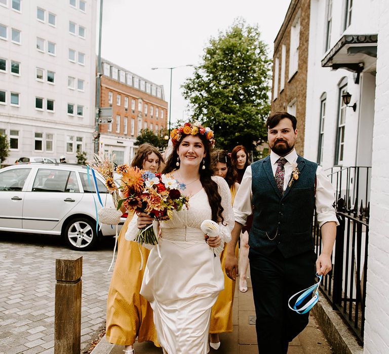 Bride & groom hold hands as they walk down the street with one another on their wedding day