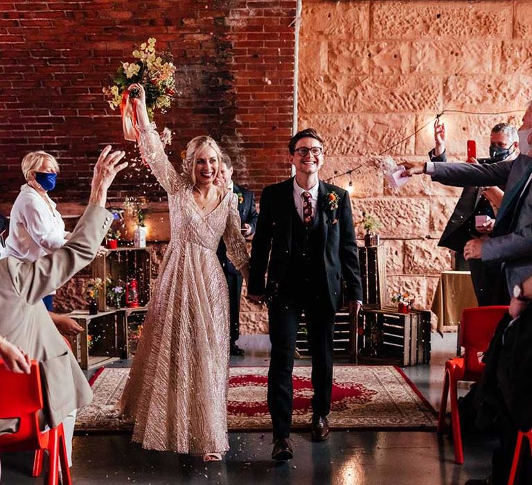 Bride lifts her bouquet in the air after wedding ceremony