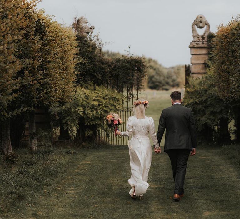 Bride and groom stroll hand in hand through Hellens Manor gardens