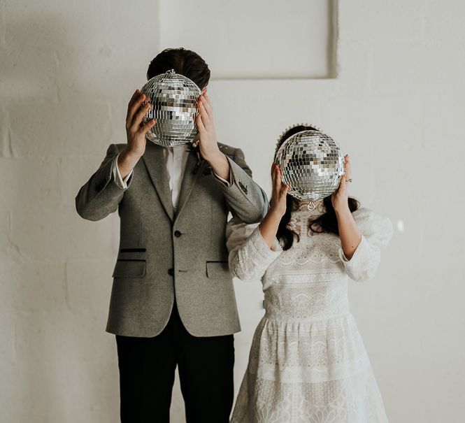 Bride & groom hold up disco ball in front of their faces on their wedding day