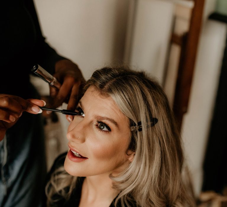 Bride with blonde hair has her make up done before her wedding