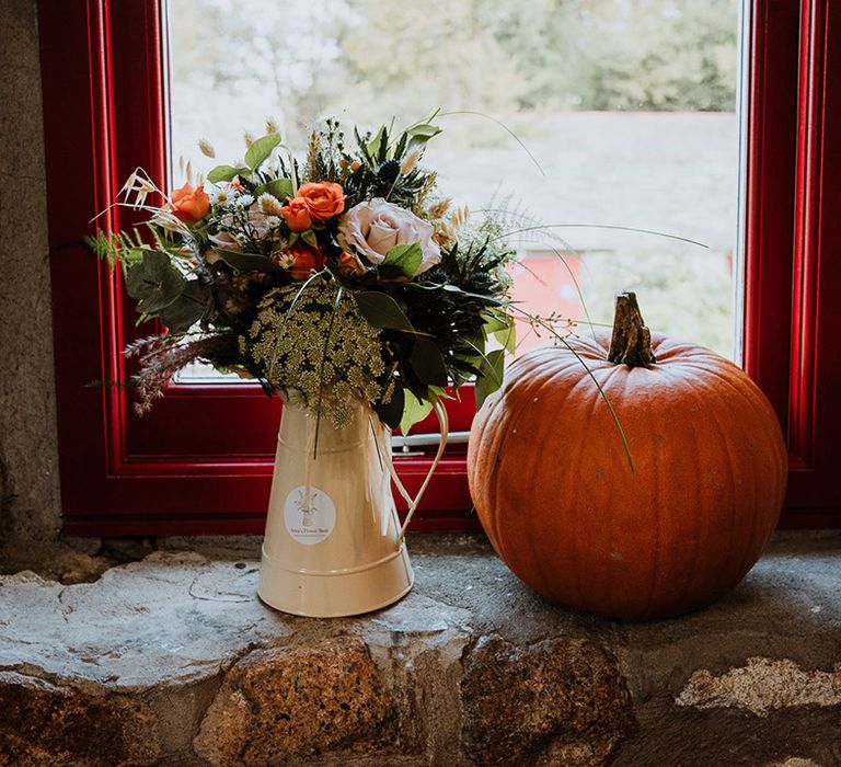 Pumpkin beside floral bouquet in vase 