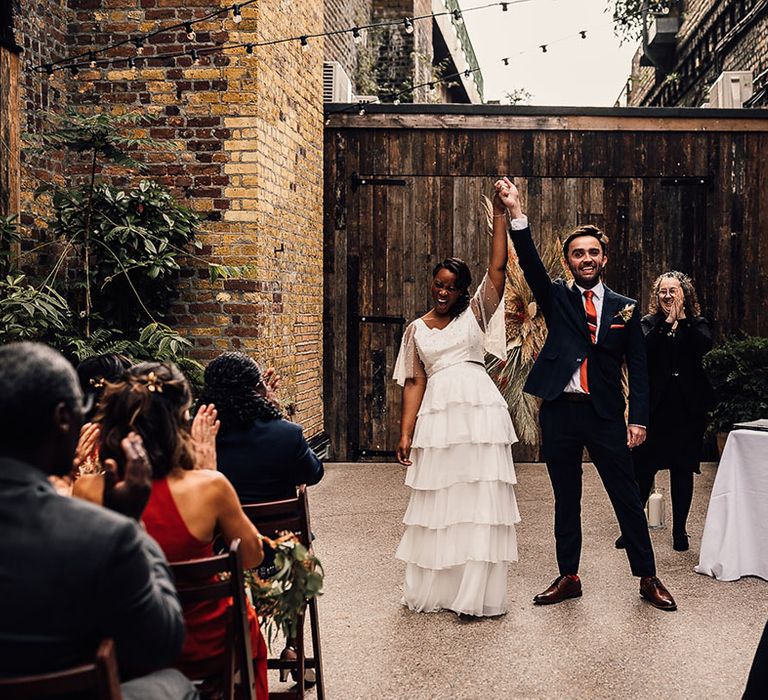 Civil wedding ceremony at 100 Barrington with bride in a layered skirt and pearl top holding hands with her groom in a navy suit at the altar 