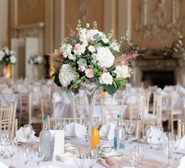 Large floral bouquet sits in the middle of table for wedding reception