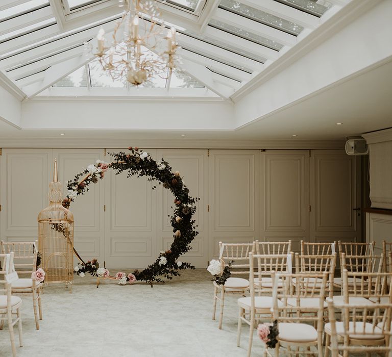 Floral circular archway complete with pink roses and large gilded golden birdcage to the front of aisle