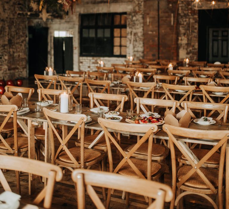 Long wooden tables with wooden chairs in reception room at industrial wedding venue in Liverpool