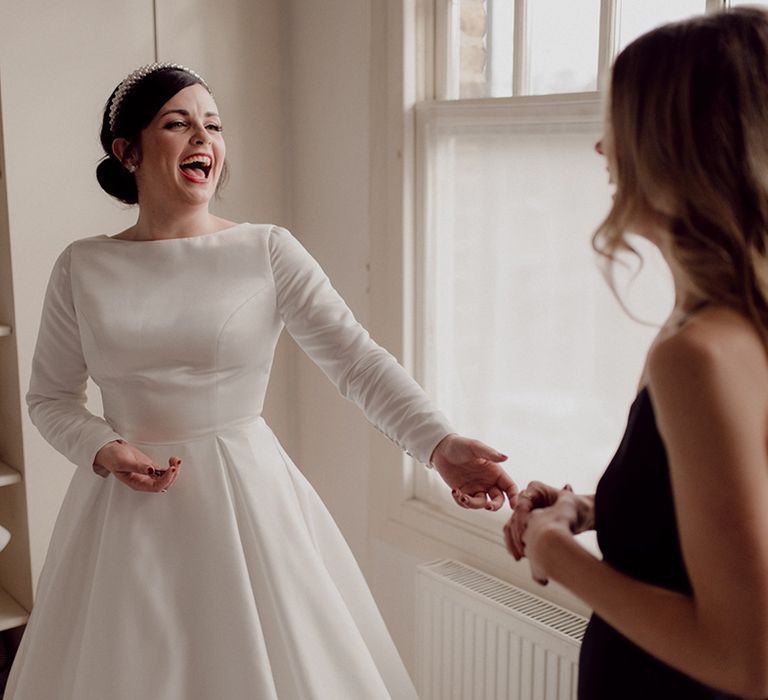 Bride in long sleeve high neck pleated wedding dress with updo complete with pearl headband 