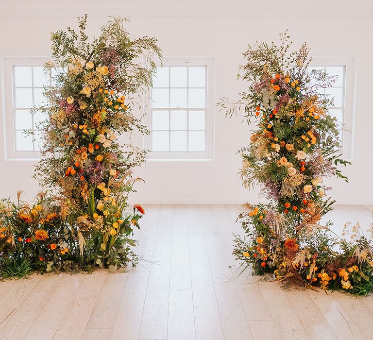 Orange, yellow and green foliage column wedding flower arrangement at minimalist wedding venue 