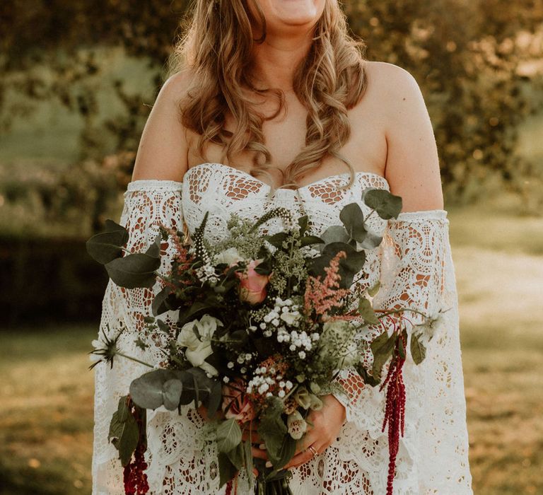 Bride in lace wedding dress with custom sleeves and pink rose flower crown holding pink and white wedding bouquet