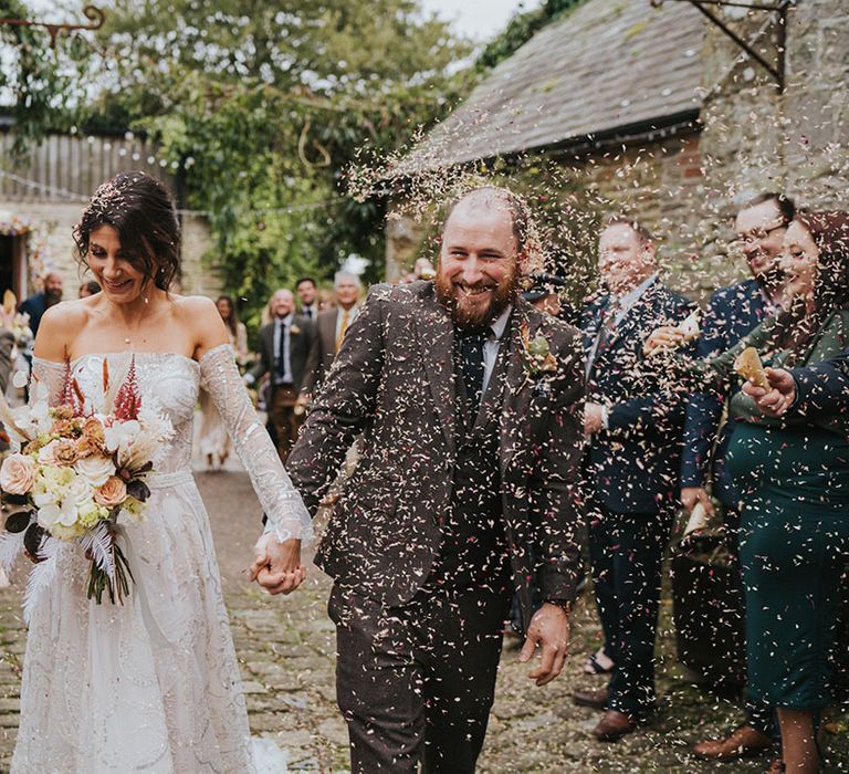 Bride and groom walk through confetti together