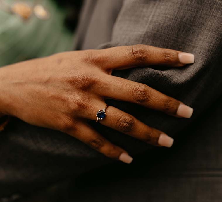 Bride showing dark blue gem wedding ring and golden bangle 