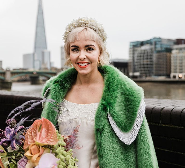 Bride with short blonde hair and white flower headband with green fur coat and white wedding dress