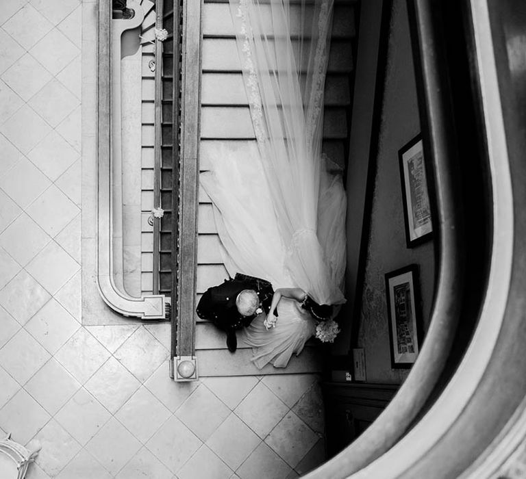 Bride walks down the steps in princess wedding dress and cathedral length nail 