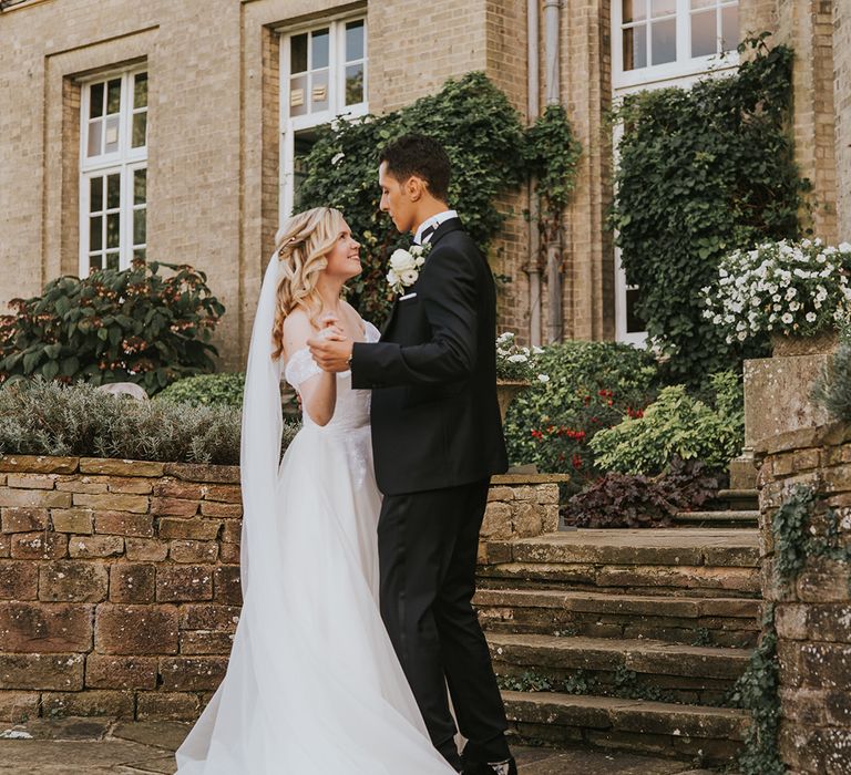 Bride and groom hold hands together for their country house wedding 