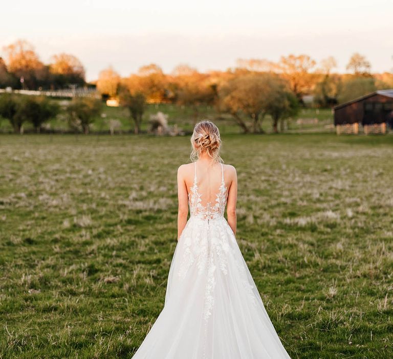 Bride in illusion back tulle wedding dress with a long train from Madison James 