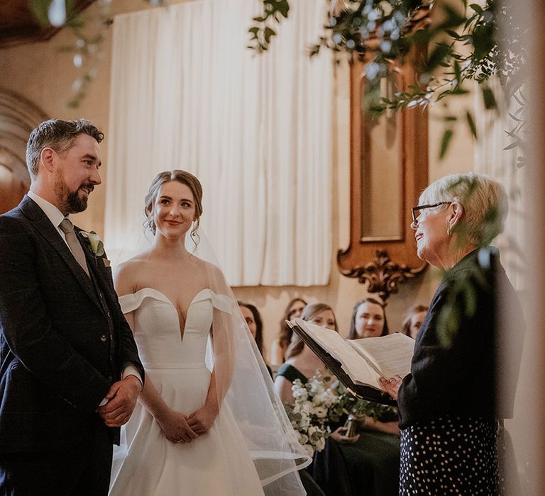 Bride and groom stand at the altar smiling as their celebrant conducts the ceremony 