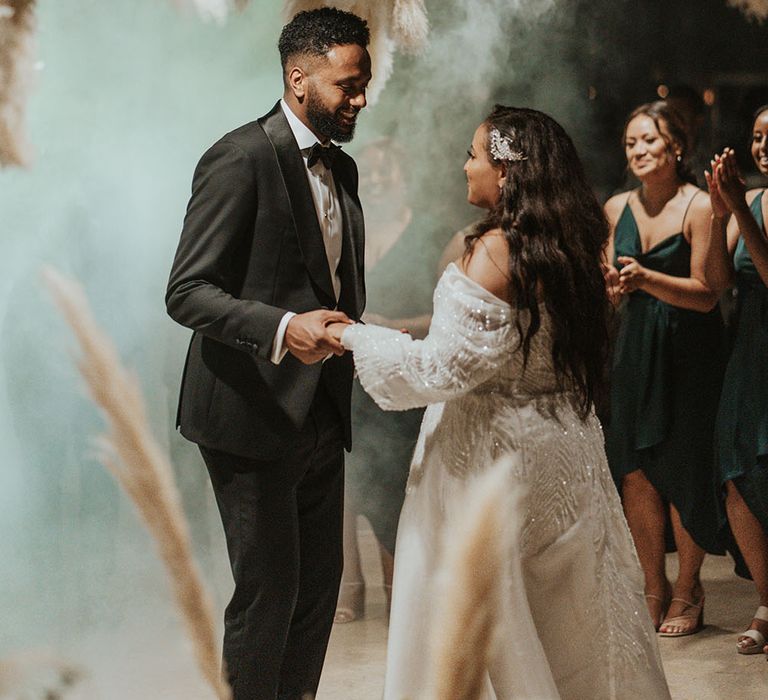 Bride & groom surrounded by pampas grass florals and smoke during first dance at wedding reception 