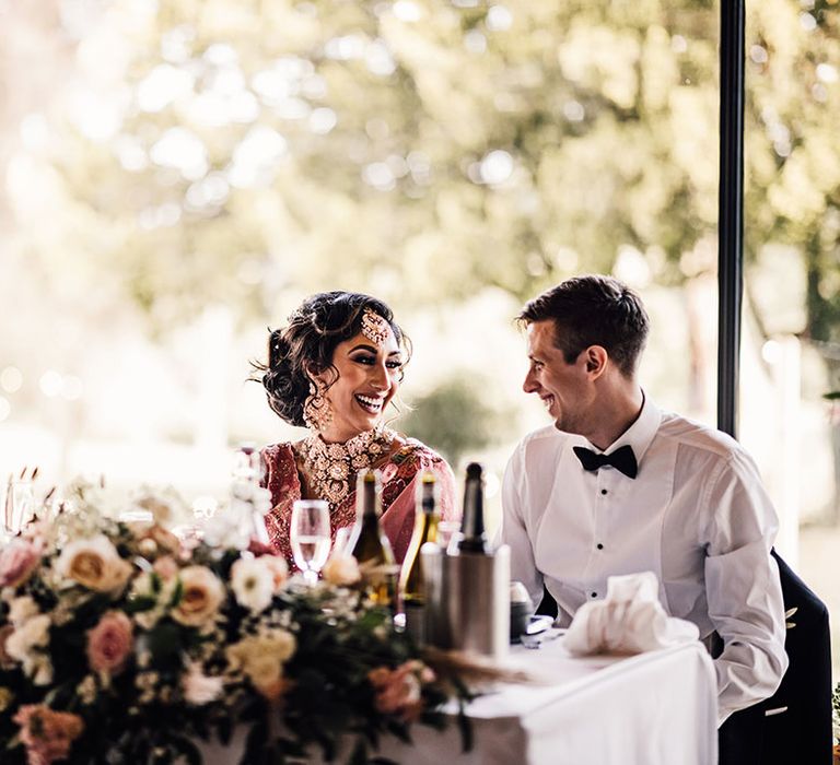 Bride & groom sit at the sweetheart table for reception 