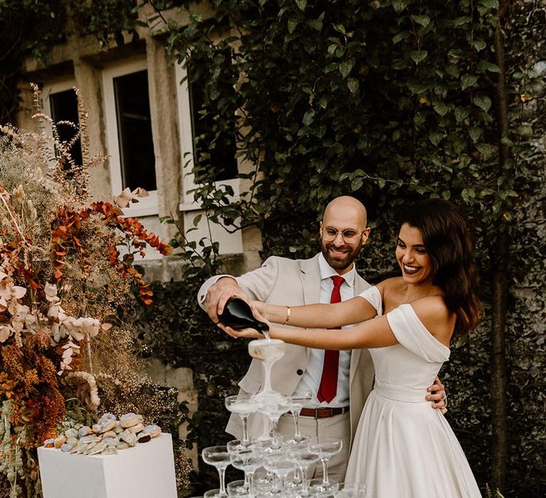 Outdoor dessert station with the bride and groom pouring champagne over their champagne tower 