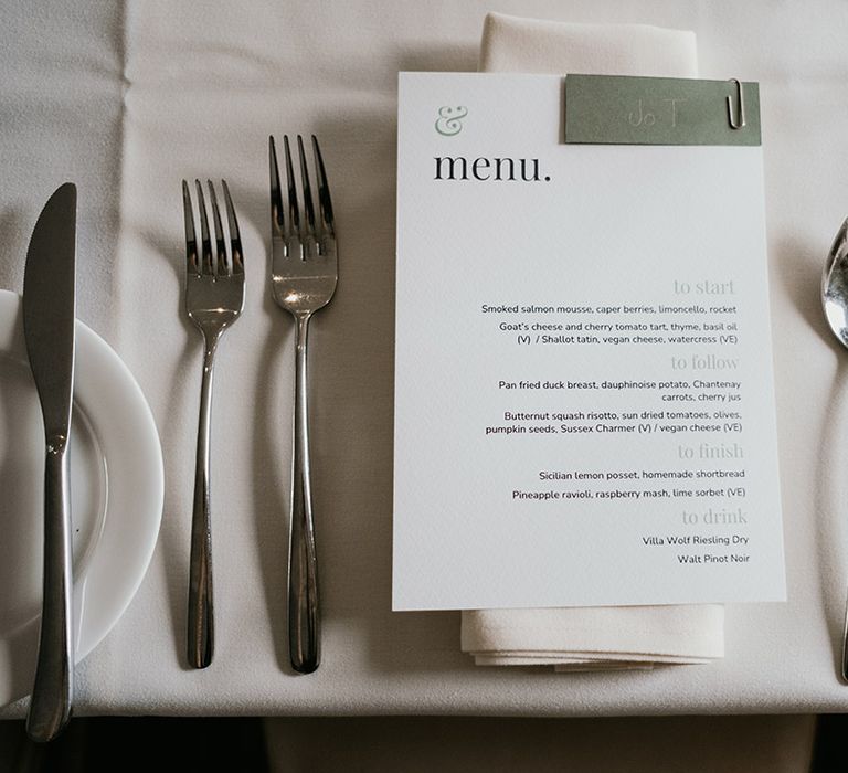 Minimalistic white and sage green wedding menu with sage green napkin and menu holder