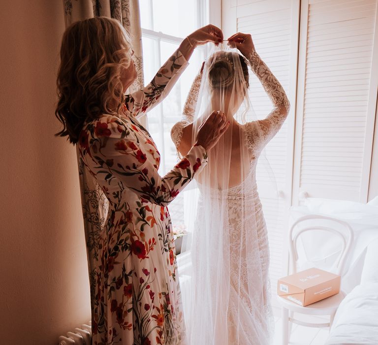 Bride wears cathedral veil and low back wedding dress with long sleeves 