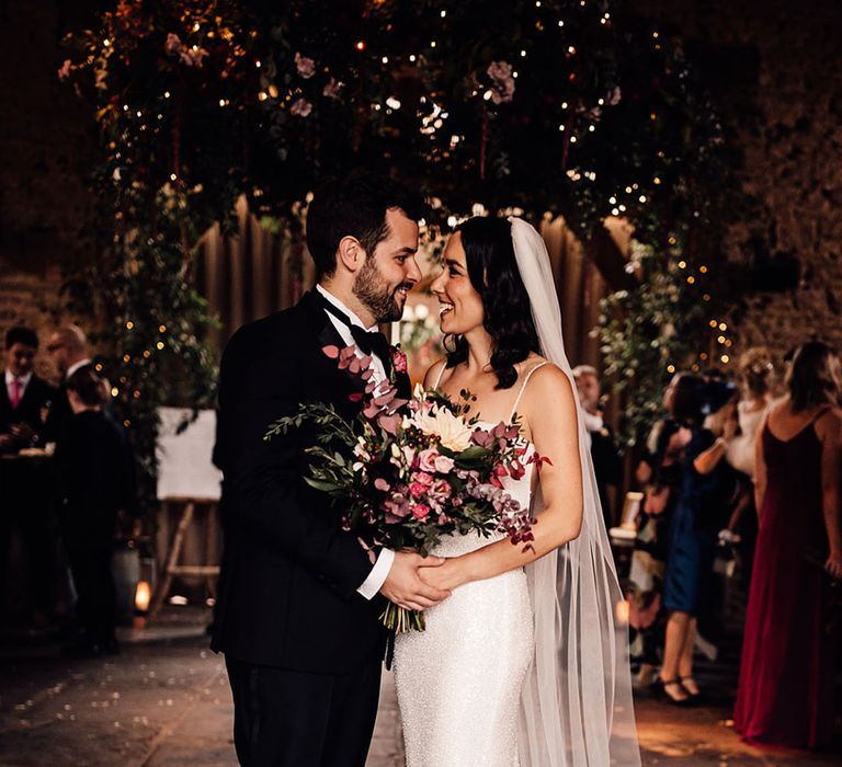 Bride in a beaded sparkle wedding dress from Made With Love gazes into the groom's eyes 