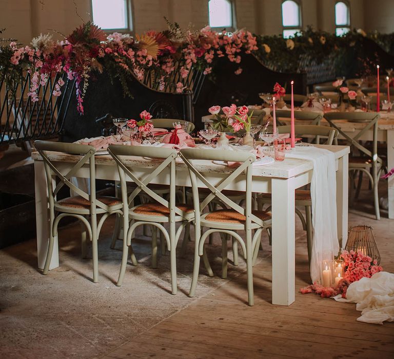 Pink theme wedding reception with pink flower installation, pink flower table decor to match the pink taper candles, napkins, and glassware 