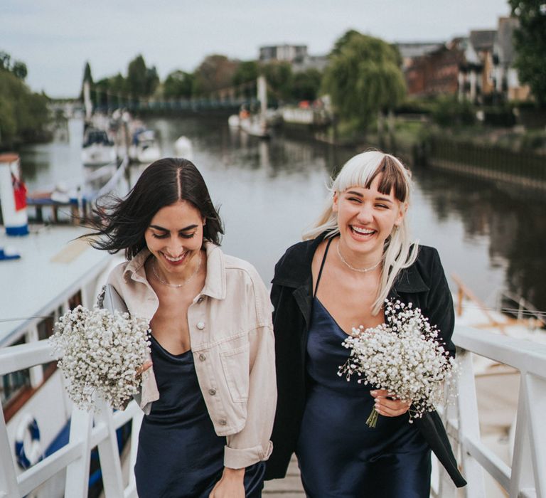 Bridesmaids in navy midi bridesmaid dresses carry babys breath bouquets 