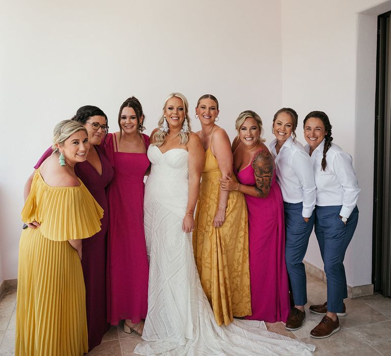 Bride stands with her bridesmaids in mismatched bridesmaid dresses in vibrant colours