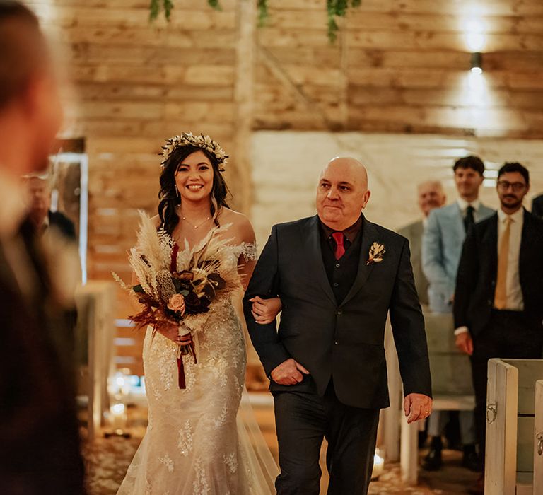 Father of the bride in black suit with red tie walks the bride in a lace off the shoulder wedding dress downtime aisle for autumnal wedding at Milling Barn