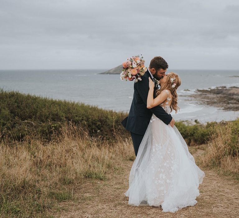 The bride and groom share a kiss at their at home coastal wedding in Devon 