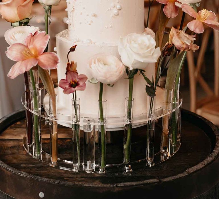 Three tier iced buttercream wedding cake with pearl decorations, test tube vases and dried blush toned florals 