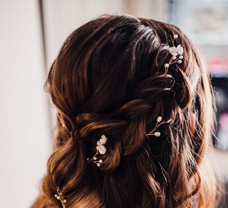 Bride with braided brown hair decorated with gold and pearl flower hair accessory for pretty wedding hairstyle 