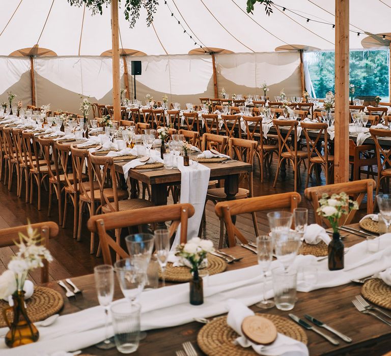 Marquee wedding at Willow Grange Farm sustainable wedding venue in Cambridgeshire with long banquet tables decorated with wicker placemats and wood slice place names