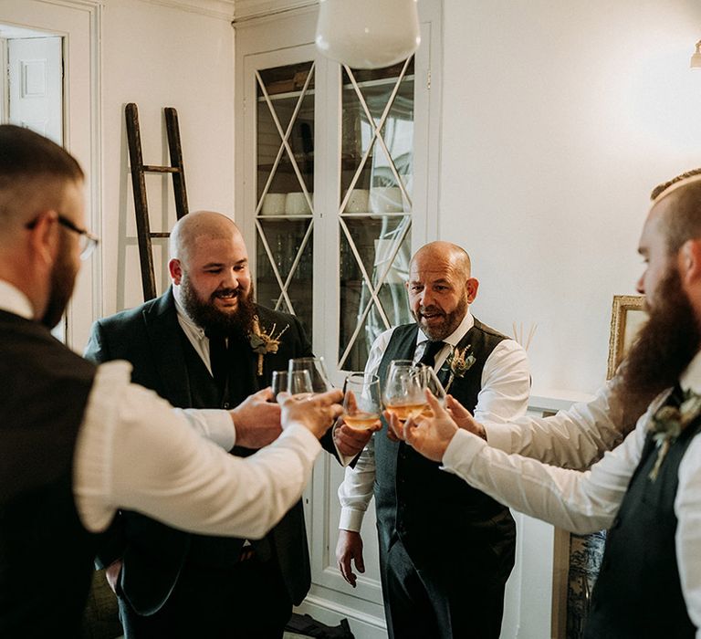 Groom and groomsmen share a shot of whiskey on the morning of the wedding 