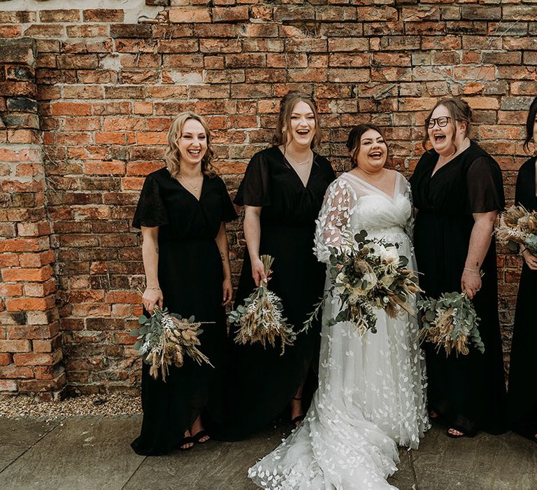 Bridal party in black bridesmaid dresses with the bride in long sleeve lace wedding dress